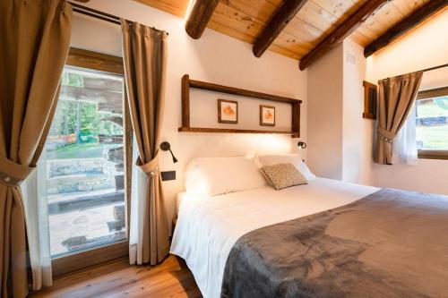 a bedroom with a bed and a large window at Raccard Resort de Montagne in Torgnon