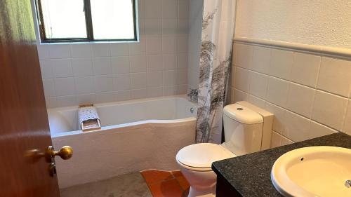 a bathroom with a toilet and a tub and a sink at White River Selfcatering at Greenway woods House no 9 in White River