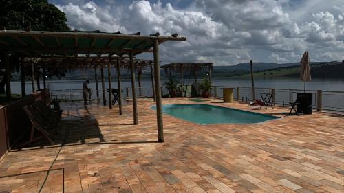 uma piscina com um pavilhão ao lado de uma massa de água em Canto do lago pousada em Guapé