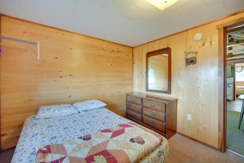 a bedroom with a bed and a wooden wall at Stone Lake Cabin with Private Deck and Fire Pit! in Northwoods Beach