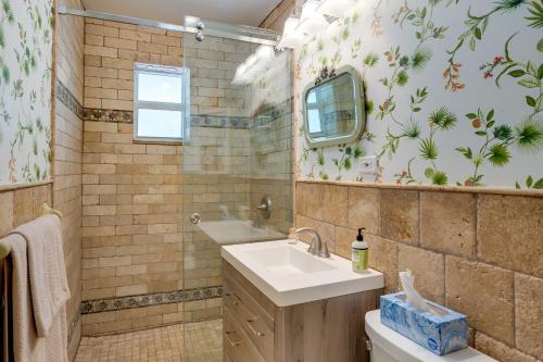 a bathroom with a sink and a shower and a mirror at West Palm Beach Home with Fenced-In Yard and Deck! in West Palm Beach