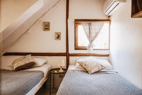 Duas camas num pequeno quarto com uma janela em Griss Lodge & Villas em Santa Teresa