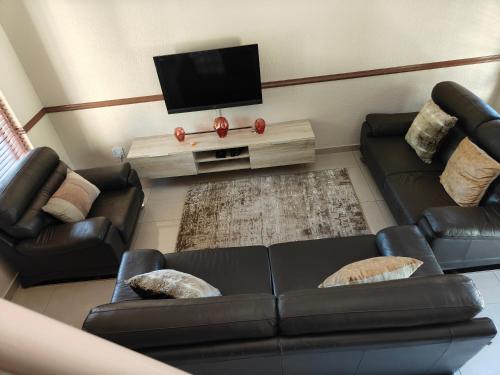 a living room with two leather couches and a flat screen tv at Unit 89 Pendleberry Holiday Resort in Bela-Bela