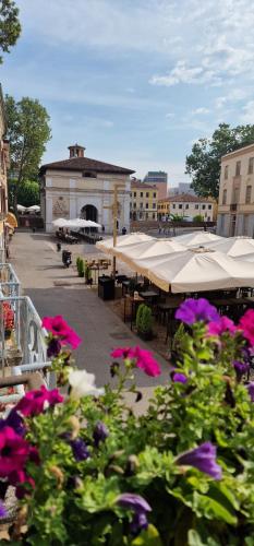 a group of flowers in a courtyard with tables and umbrellas at Elegante alloggio in casa storica-Borgo Portello in Padova