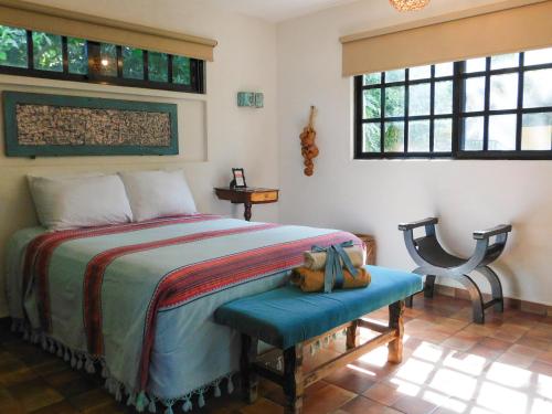 a bedroom with a bed and a chair and windows at Hotel Boutique Casa Flor de Mayo in Mérida