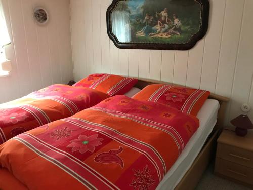 duas camas num quarto com cobertores vermelhos e laranja em Ferienwohnung Niederottendorf em Neustadt in Sachsen