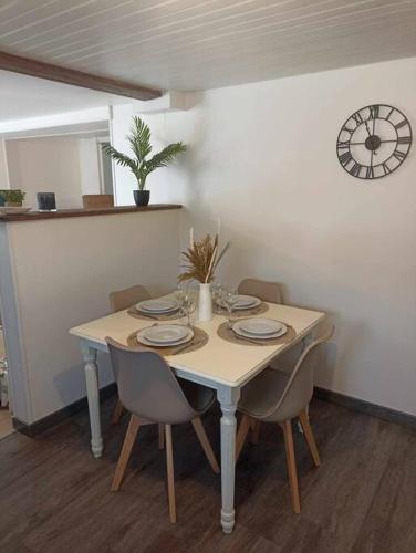 une table à manger avec des chaises et une horloge murale dans l'établissement A Bigeo, à Saint-Sauveur-Marville