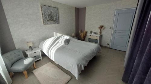 une chambre avec un lit blanc et une chaise dans l'établissement Nature et Hotes, à Quiers-sur-Bézonde