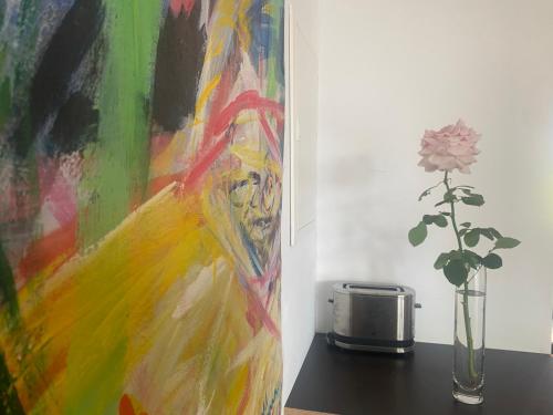a painting sitting next to a vase with a flower at Loft mit Dachterrasse in Bernau am Chiemsee