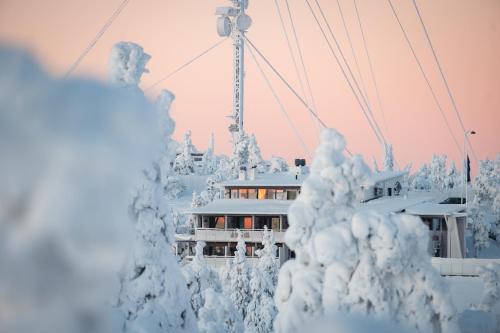 a building in the snow with snow covered trees at Ruka Peak - Boutique Hotel & Restaurant in Ruka