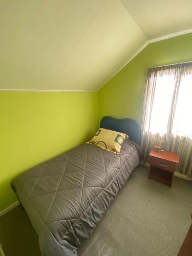 ein kleines Schlafzimmer mit einem Bett und einem Fenster in der Unterkunft Calor y amor de hogar chilote in Castro