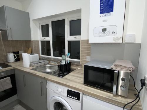 a kitchen with a sink and a microwave at Cosy 3BD Guesthouse w/ Private Bathrooms in Northampton