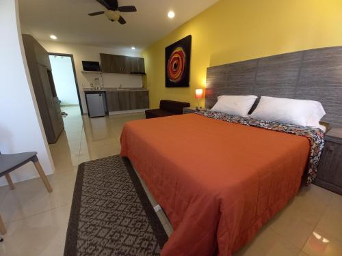 a bedroom with a large orange bed and a kitchen at Tu Estancia Guadalajara in Guadalajara