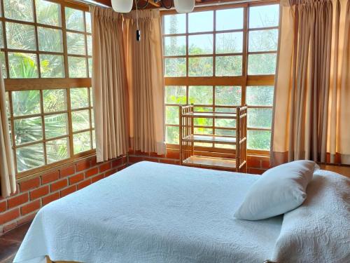 een slaapkamer met een wit bed en grote ramen bij Casa del Gringo in Cieneguilla