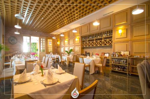 un comedor con mesas y sillas blancas y un restaurante en NBT Hotel Lac en Laç