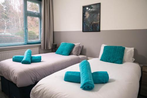 two beds in a room with blue pillows on them at Central City Castle Apartment with FREE parking in Nottingham