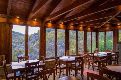 a dining room with tables and chairs and windows at Kipi Mountain Resort in Kipoi