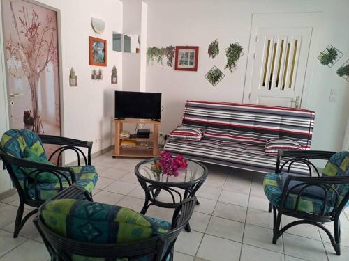 a living room with a couch and chairs and a tv at T2 cosy, spacieux et confortable in Les Trois-Îlets