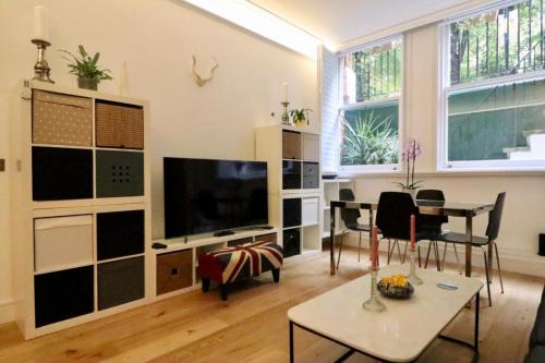 sala de estar con TV de pantalla plana y mesa en Luxury Apartment South Kensington en Londres