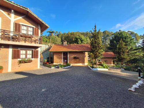 a house with a driveway next to a building at Pousada Encanto da Serra in Monte Verde