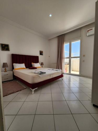 a bedroom with a large bed and a large window at Duplex bien equipe securise avec jardin et veranda in La Marsa