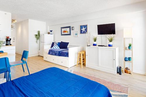 a bedroom with a blue bed and a kitchen at Delights in Daytona Unit 525 in Daytona Beach