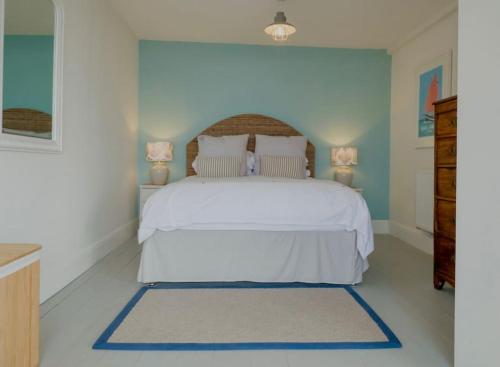 a bedroom with a white bed and two lamps at Mesmerising sea views - Penrose - above the beach Cornwall. in Downderry