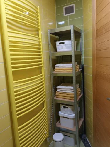baño con paredes amarillas y estante con toallas en Sweet Country House, en Markovci