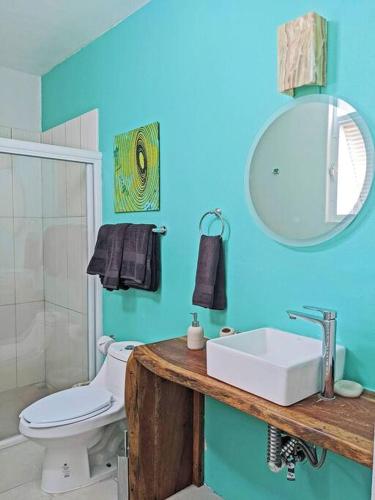 a bathroom with a sink and a toilet and a mirror at 2BR -Water at Mikasa- Fast WIFI, King beds, AC, Near beach, Pool in Puerto Escondido