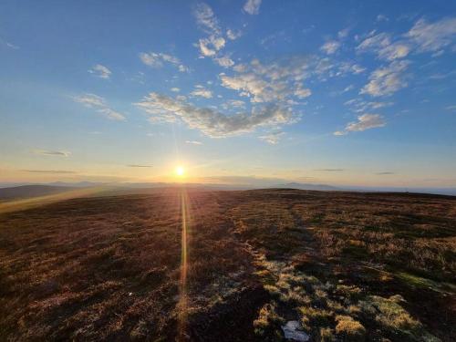 an open field with the sun setting in the sky at Cozy mountain house in Jämtland in Vallrun