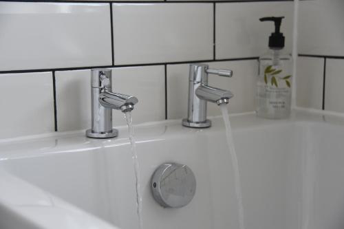 a bathroom sink with two faucets and water at Maen Llwyd in Llanyre
