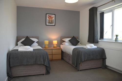 a bedroom with two beds and two lamps and a window at Maen Llwyd in Llanyre