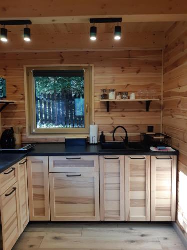 una cucina con armadi in legno, lavandino e finestra di Domki na granicy 