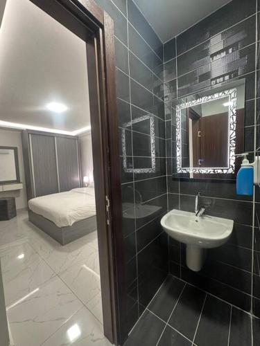 a bathroom with a sink and a mirror and a bed at cozy rooftop near al services 23 in Rujm ash Sharāʼirah
