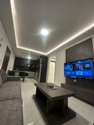 a living room with a couch and a flat screen tv at cozy rooftop near al services 23 in Rujm ash Sharāʼirah