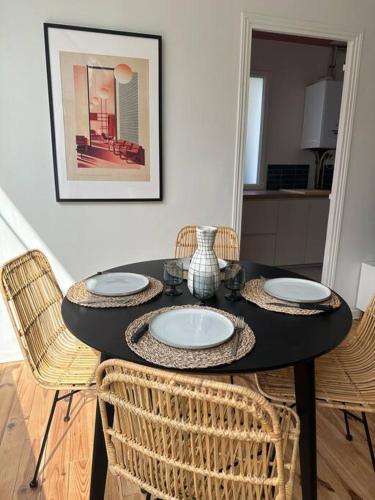 a black table with wicker chairs in a room at Le Studio 41 in Caen