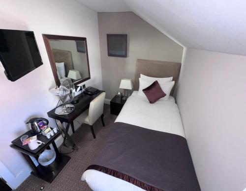 a bedroom with a bed and a desk with a mirror at Duke Of Normandie in St Peter Port