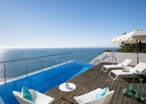a swimming pool on the deck of a house with the ocean at Villa Mar Azul in Salema