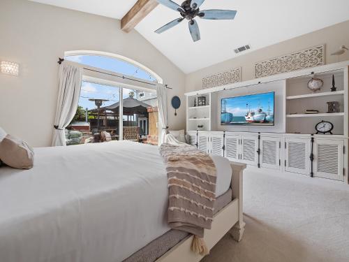 een witte slaapkamer met een groot bed en een flatscreen-tv bij Luxury beach home one block from ocean with spa, WiFi, & gorgeous outdoor space in San Diego