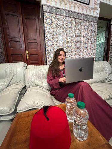 拉巴特的住宿－Dar Yassine，坐在沙发上的手提电脑的女人