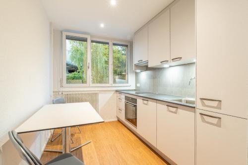 cocina con armarios blancos, mesa y ventana en Möblierte Zimmer - gratis Parkplatz, en Berna