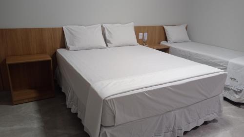 1 dormitorio con 2 camas con sábanas y almohadas blancas en Hotel Bonina en São Paulo