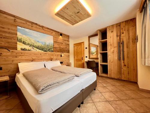 1 dormitorio con 1 cama y pared de madera en Chalet Nano, en Livigno