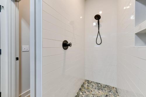 a white shower with a black shower head at The Retreat at Lake Norman Boat Dock and Pool! in Mooresville