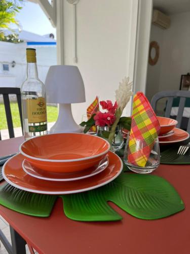 a red table with plates and a bottle of wine at Villa Ti Lanmou in Saint-François
