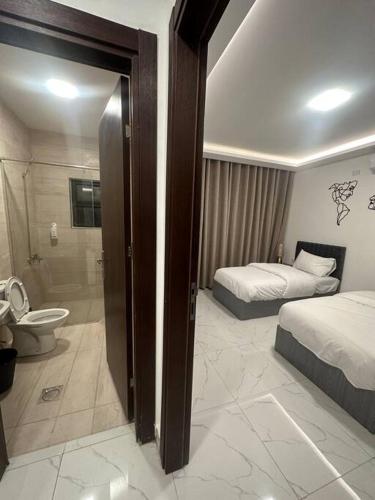 a bedroom with two beds and a bathroom with a shower at cozy rooftop near al services 24 in Rujm ash Sharāʼirah