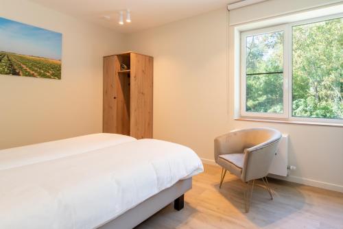 a bedroom with a bed and a chair and a window at Fluithoekhoeve in Koksijde