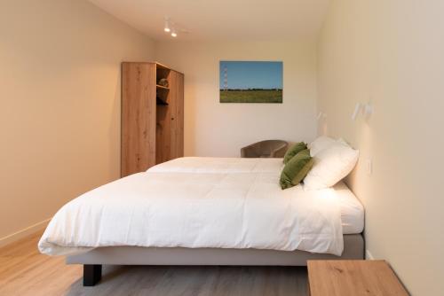 a bedroom with a white bed and a wooden table at Fluithoekhoeve in Koksijde