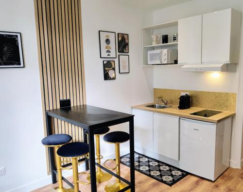 eine Küche mit einem schwarzen Tisch und 2 Hockern in der Unterkunft Confort & Style en plein coeur de Lisieux ! in Lisieux