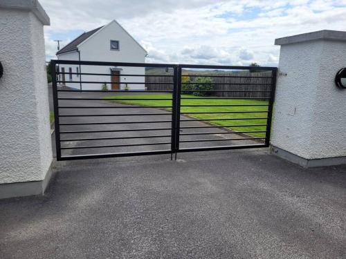 a gate to a pasture with a house in the background at Glenwood guesthouse near Ballybofey in Killygordon